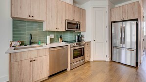 A modern kitchen with wooden cabinets, a stainless steel refrigerator, a microwave, and an oven. - Modern Atlanta Townhome Rental ~ 2 Mi to Downtown! (Atlanta)