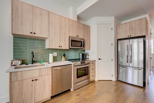 A modern kitchen with wooden cabinets, a stainless steel refrigerator, a microwave, and an oven. - Modern Atlanta Townhome Rental ~ 2 Mi to Downtown! (Atlanta)