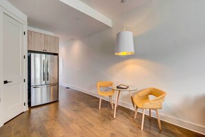 A modern kitchen with a stainless steel refrigerator, wooden cabinets, and a round glass table with two yellow chairs. - Modern Atlanta Townhome Rental ~ 2 Mi to Downtown! (Atlanta)