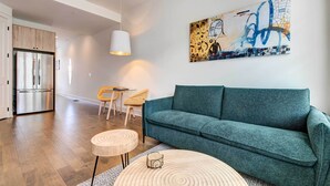 A modern living room with a teal sofa, a wooden coffee table, and a painting on the wall. - Modern Atlanta Townhome Rental ~ 2 Mi to Downtown! (Atlanta)