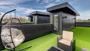 A modern outdoor patio with artificial grass, a hanging chair, and a wicker chair. - Modern Atlanta Townhome Rental ~ 2 Mi to Downtown! (Atlanta)