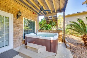 A spa area with a hot tub, wooden steps, and a ceiling fan.