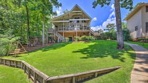 A two-story house with a large front porch, a covered deck, and a well-maintained lawn.