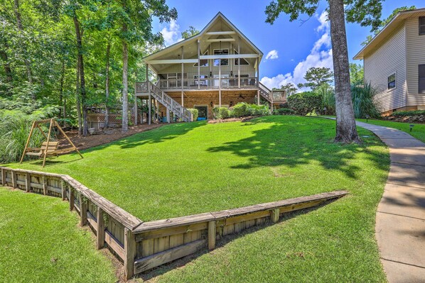 A two-story house with a large front porch, a covered deck, and a well-maintained lawn.