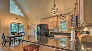 A spacious kitchen with a large island, wooden cabinets, and a hanging light fixture.