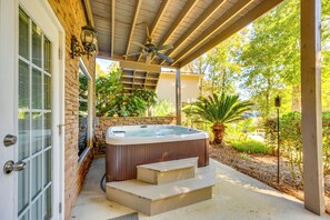 A hot tub with steps leading up to it, a covered patio area, and a brick wall.