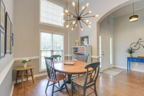 Un coin repas avec une table en bois, des chaises et un lustre moderne.