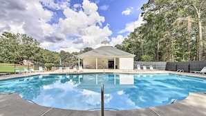 Piscina com espreguiçadeiras e um quiosque coberto.