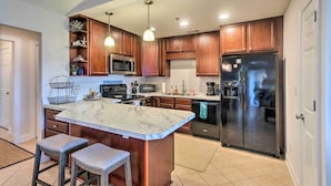 A modern kitchen with a marble island, stainless steel appliances, wooden cabinets, and pendant lighting. - 3rd-floor Riverfront Condo: Walk to Downtown Eats! (Darien)