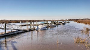 A calm waterway with docks and boats, surrounded by reeds and trees. - 3rd-floor Riverfront Condo: Walk to Downtown Eats! (Darien)