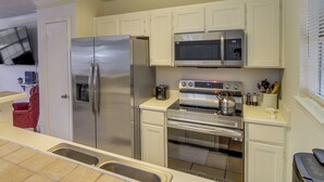 A modern kitchen with stainless steel appliances, white cabinetry, and a tiled backsplash.