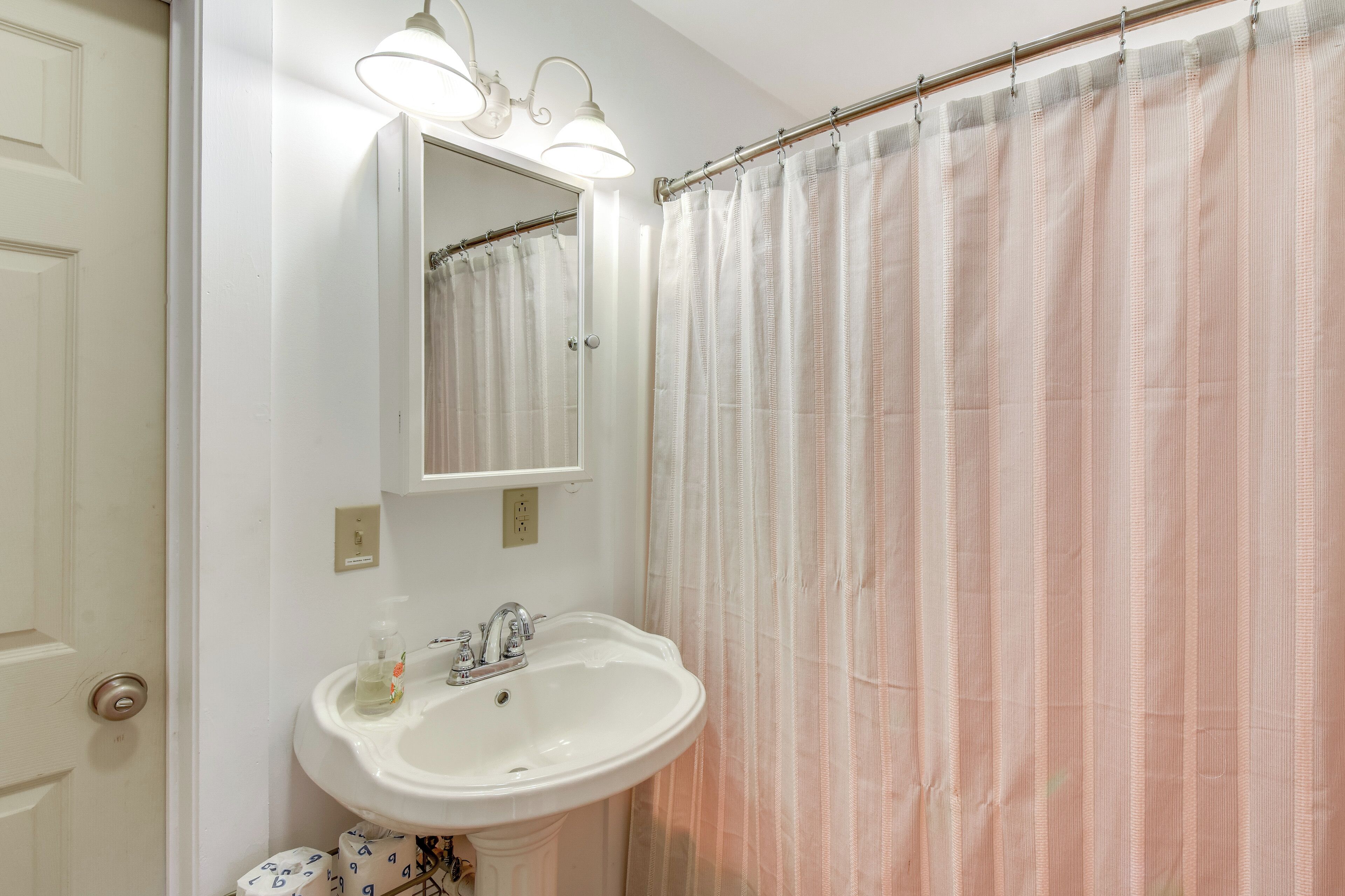 Un baño con lavabo blanco, espejo y cortina de ducha.
