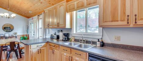 A kitchen with wooden cabinets, a dishwasher, a sink, and a window providing natural light.