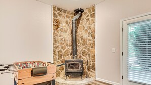 A cozy room with a stone wall, a wood-burning stove, and a foosball table. - Hiawassee Cabin < 10 Mi to Lake Chatuge! (Hiawassee)