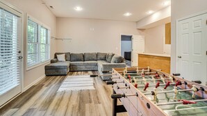 A living room with a sectional sofa, a foosball table, and a kitchen area in the background. - Hiawassee Cabin < 10 Mi to Lake Chatuge! (Hiawassee)