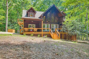 Eine zweistöckige Holzblockhütte mit einer Holzterrasse und einer Treppe, die zum oberen Stockwerk führt.