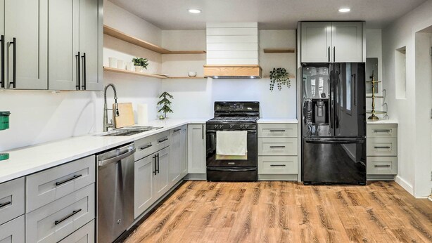 A modern kitchen with grey cabinets, a black stove, and a stainless steel dishwasher.