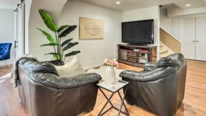 A living room with leather sofas, a flat-screen TV, a potted plant, and a framed certificate on the wall.
