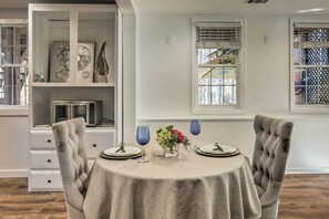 A dining area with a round table, two upholstered chairs, a vase with flowers, and blue wine glasses. - Atlanta-area Retreat Near Lake: Pet Friendly! (Peachtree City)