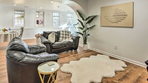 A modern living room with a leather sofa, a round coffee table, and a white shag rug.