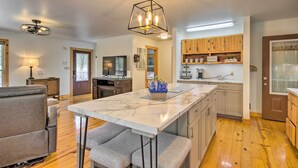 A modern kitchen with wooden cabinets, a marble island, and a pendant light.