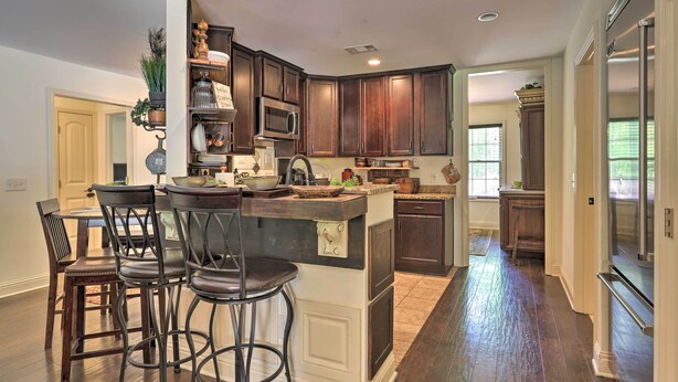 Una cocina con armarios de madera oscura, una isla central con taburetes de bar, un microondas y un refrigerador.
