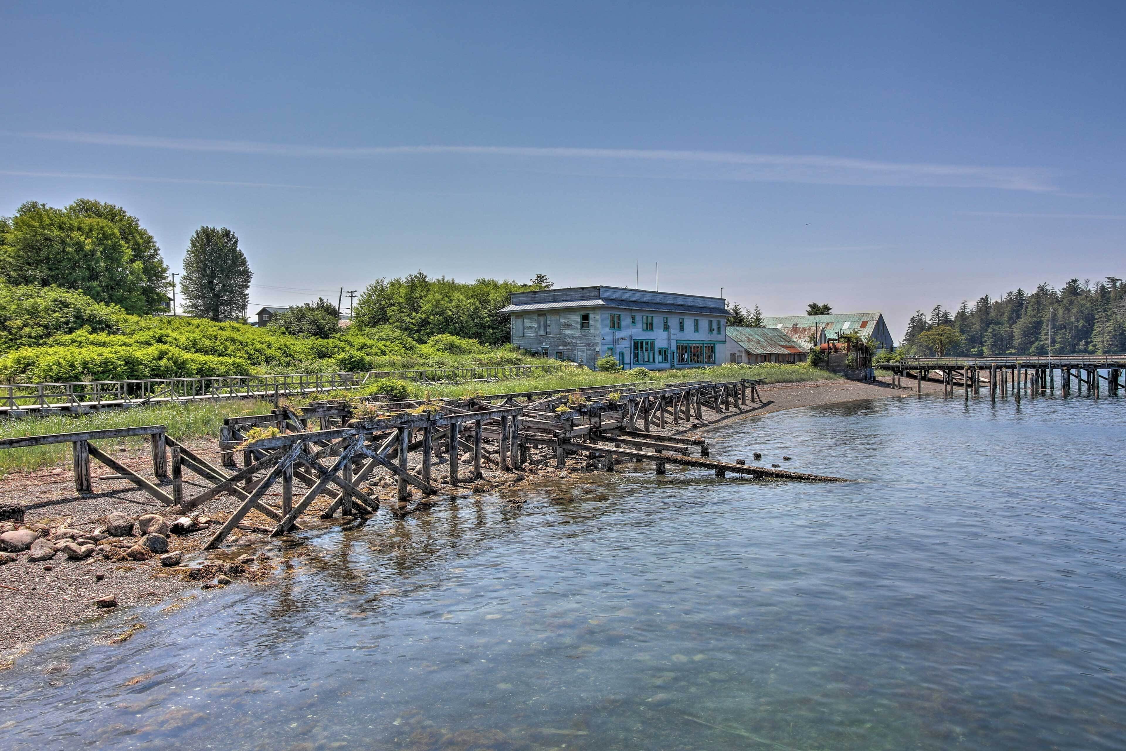 A riverside building with a dock extending into the water, surrounded by greenery and trees.