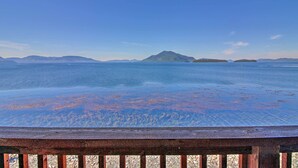 Eine Holzterrasse mit Blick auf ein ruhiges Meer und entfernte Inseln.
