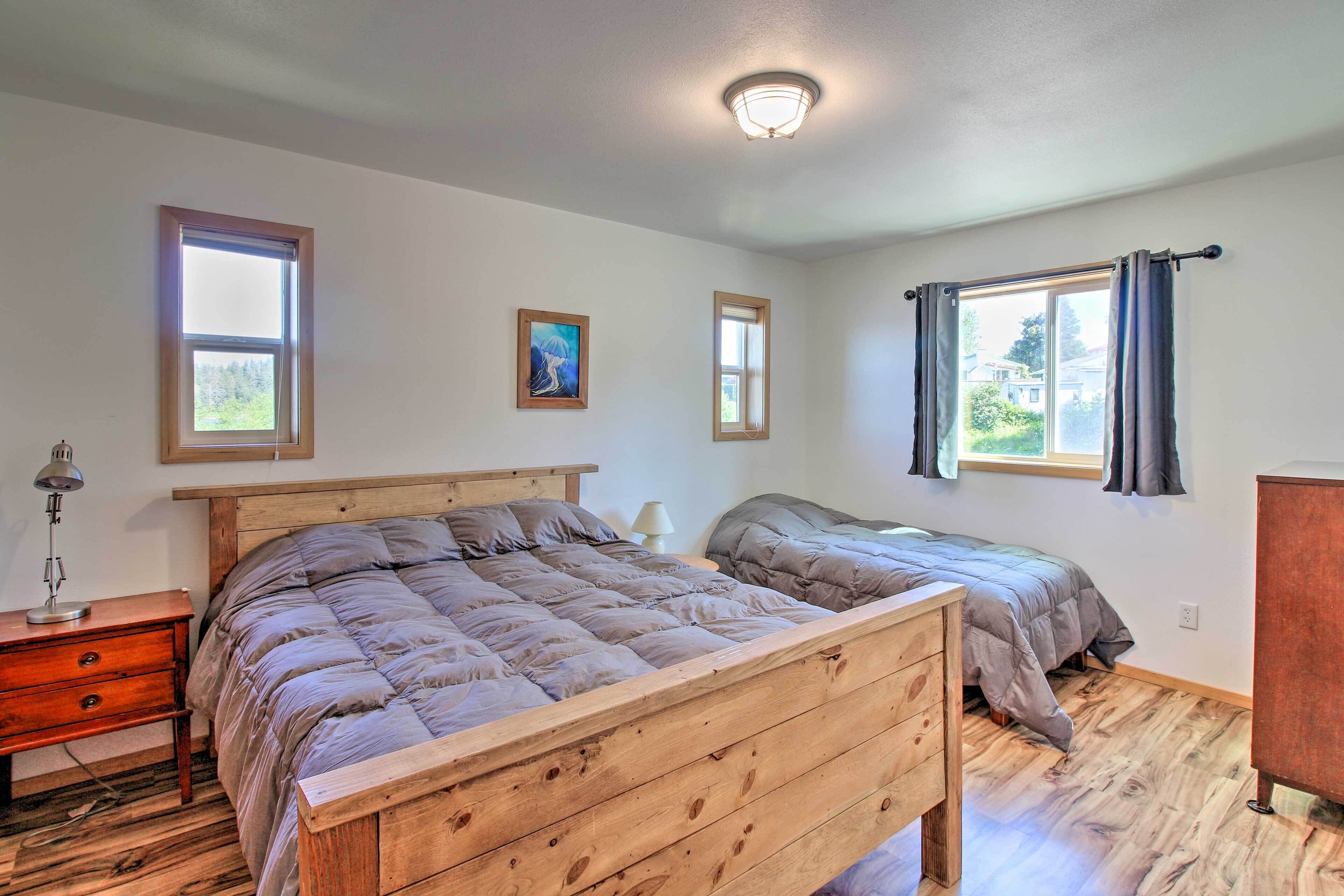 A bedroom with two beds, wooden headboards, a nightstand with a lamp, and a dresser.