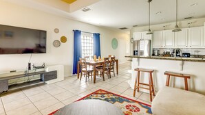 A modern kitchen with white cabinets, a built-in oven, and a coffee machine.