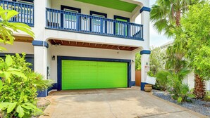 A two-story building with a green garage door, blue railings, and a balcony.