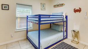 Dormitorio con literas, una ventana, una alfombra pequeña y adornos en la pared, incluyendo un mapa y un cangrejo.