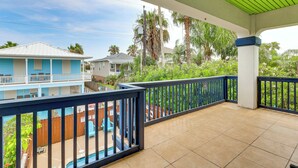 Un espacio al aire libre techado con una piscina, un edificio azul y vistas a casas vecinas.