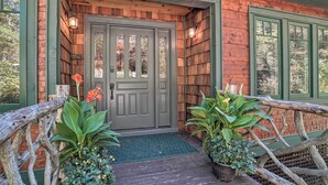 A rustic wooden cabin with a green door, two potted plants, and a wooden fence. - Riverfront Tallulah Falls Cabin w/ Hot Tub! (Lakemont)