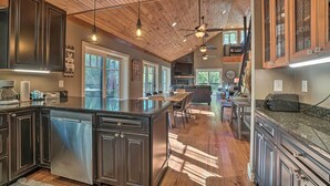 A spacious kitchen with dark cabinetry, a central island, and pendant lighting. - Riverfront Tallulah Falls Cabin w/ Hot Tub! (Lakemont)