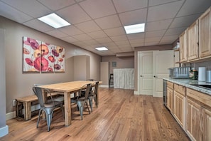 A spacious kitchen with wooden cabinets, a dining table with chairs, and a large painting on the wall. - Riverfront Tallulah Falls Cabin w/ Hot Tub! (Lakemont)