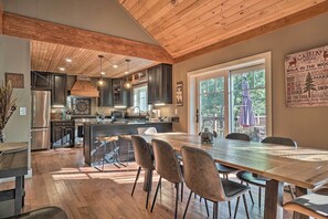 A spacious kitchen with dark cabinets, a large island, and a dining area with a wooden table and chairs. - Riverfront Tallulah Falls Cabin w/ Hot Tub! (Lakemont)