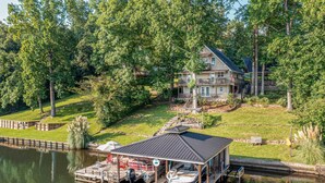 Une propriété au bord du lac, dotée d’un quai, d’un abri à bateaux et d’une grande maison entourée d’arbres.
