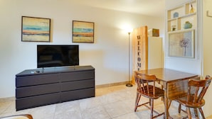 A room with a TV on a black dresser, two wooden chairs, a wooden table, and a 'WELCOME' sign. - Budget-friendly Tucson Studio: 2 Mi to University! (Tucson)