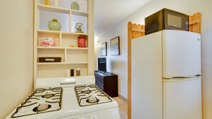 A kitchen with a stove, refrigerator, and shelves with various items. - Budget-friendly Tucson Studio: 2 Mi to University! (Tucson)
