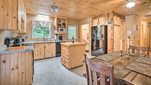 Una cocina de madera con una isla central, electrodomésticos integrados y un comedor con mesa y sillas.