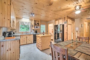 Una cocina de madera con una isla central, electrodomésticos integrados y un comedor con mesa y sillas.