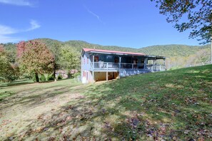 A two-story house with a balcony, surrounded by a grassy landscape and trees. - Hot Tub & Fire Pit: Pet-friendly Clayton Escape! (Clayton)