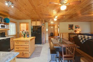 A wooden interior with a kitchen, dining area, and living space. - Hot Tub & Fire Pit: Pet-friendly Clayton Escape! (Clayton)