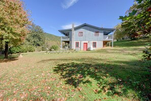 A two-story building with a red door and windows, surrounded by a grassy area with scattered leaves. - Hot Tub & Fire Pit: Pet-friendly Clayton Escape! (Clayton)