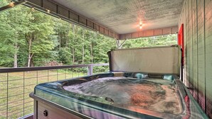 Un jacuzzi en un área exterior techada con vista a un bosque.