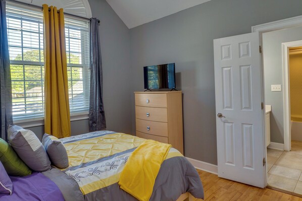 A bedroom with a bed, a dresser, a painting, and a door.