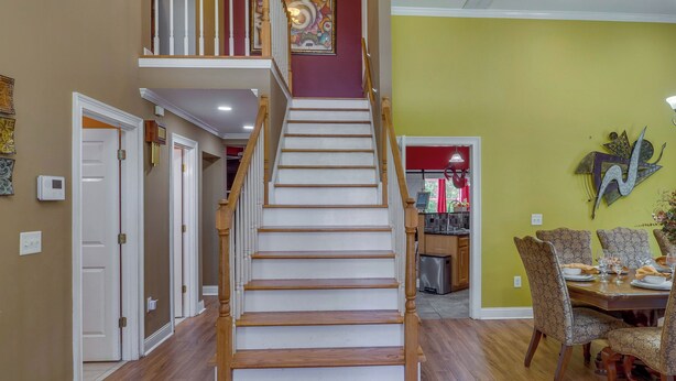 Eine Treppe mit Holzboden und weißen Geländern, die zu einer zweiten Etage führt.