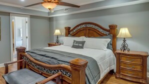 Ein Schlafzimmer mit einem hölzernen Bett, zwei Nachttischen mit Lampen, einem Deckenventilator und einem Sessel.