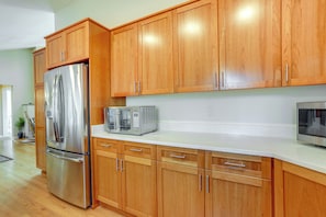 A kitchen with wooden cabinets, stainless steel appliances, and a white countertop. - Beautiful Seattle Home w/ Patio ~ 9 Mi to Downtown (Seattle)
